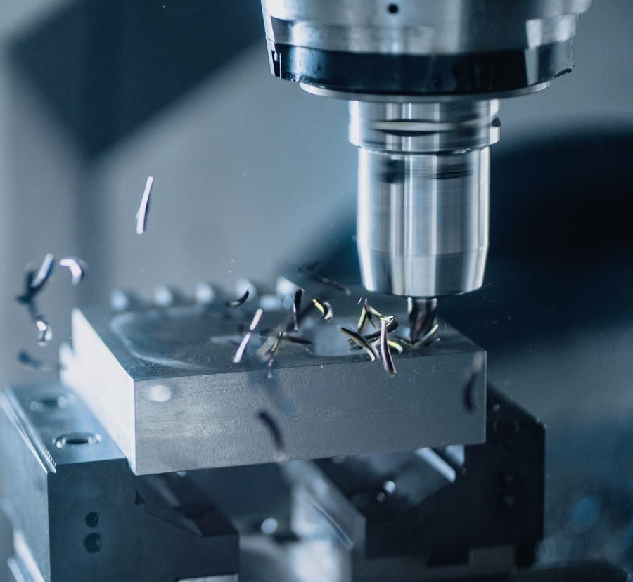 An end mill in a CNC spindle throwing curled steel chips off a block