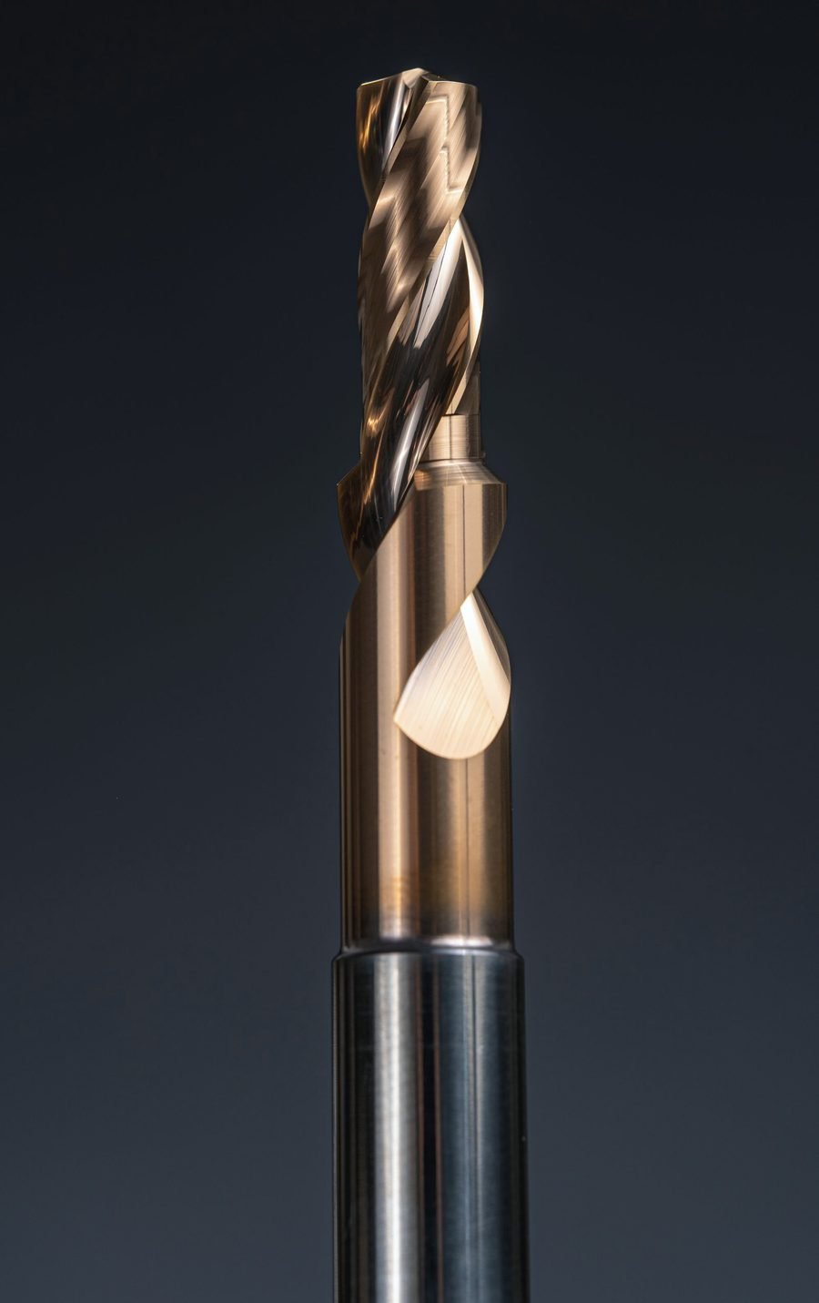 A gold TiN-coated carbide end mill held upright against a dark background