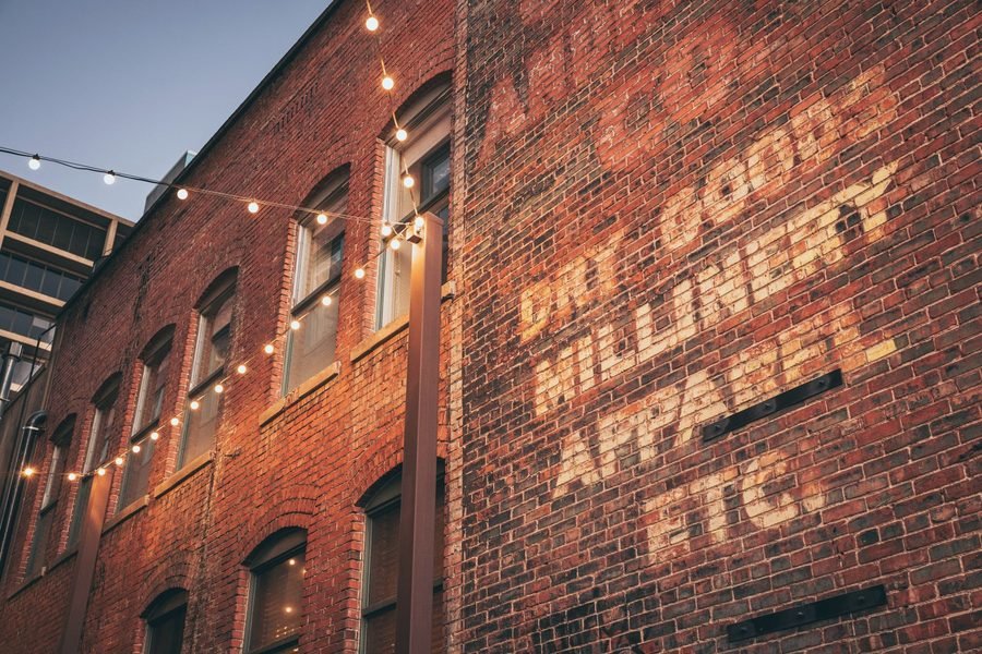 A faded painted sign for dry goods and millinery on an old brick wall